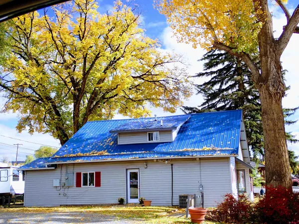 a backyard of a house with table and chairs under an umbrella