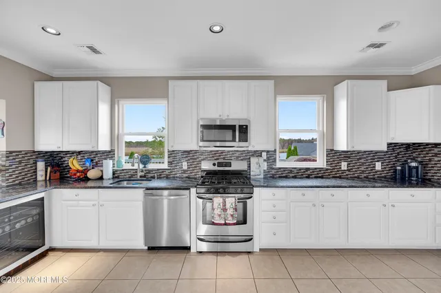 a large white kitchen with granite countertop a stove top oven a sink a dining table and chairs