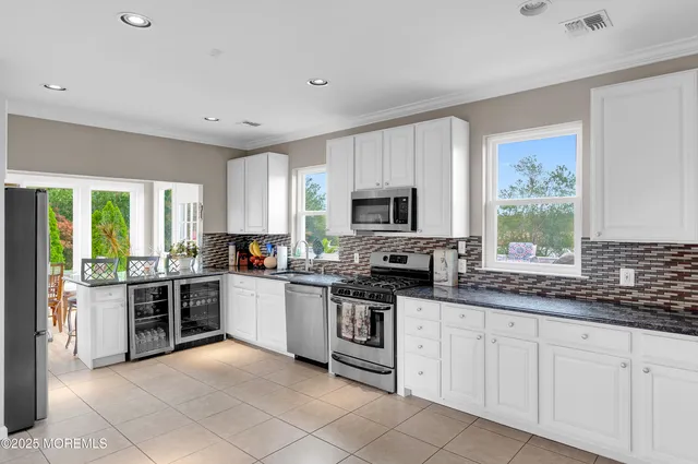 a large white kitchen with a large window and stainless steel appliances