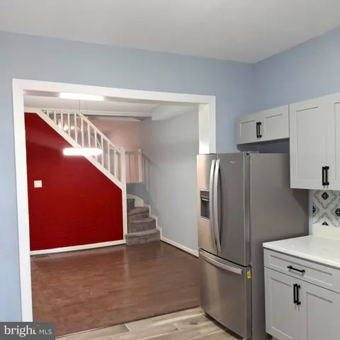 a view of a refrigerator in kitchen and an empty room