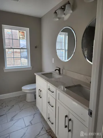 a bathroom with a granite countertop toilet sink and mirror