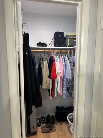 a close view of walk in closet with clothes and shoes