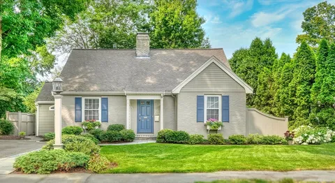 a house that is sitting in front of a big yard with potted plants