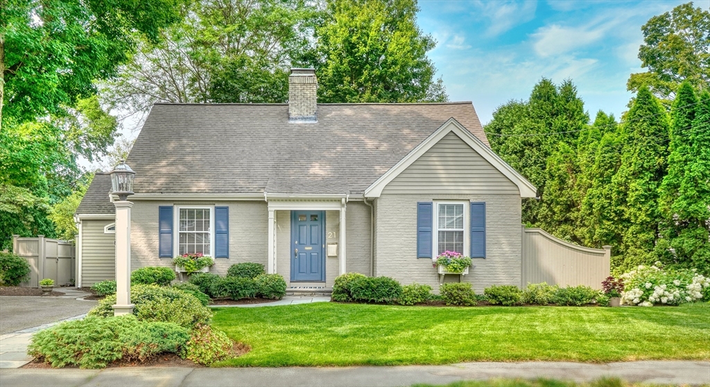 a house that is sitting in front of a big yard with potted plants