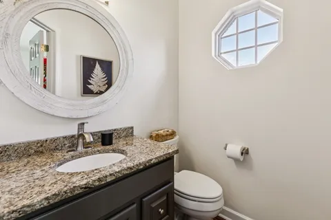 a bathroom with a granite countertop toilet a sink and mirror