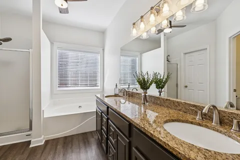 a bathroom with a granite countertop bathtub a sink and a large mirror
