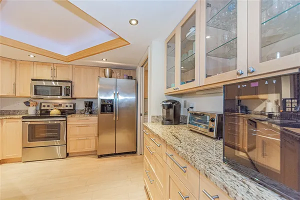 a kitchen with stainless steel appliances granite countertop a refrigerator a stove and a sink with wooden floor