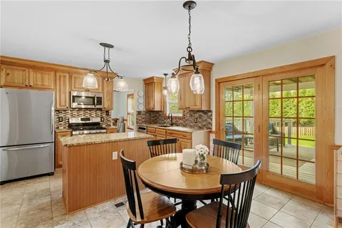 a dining room with stainless steel appliances granite countertop furniture and a chandelier