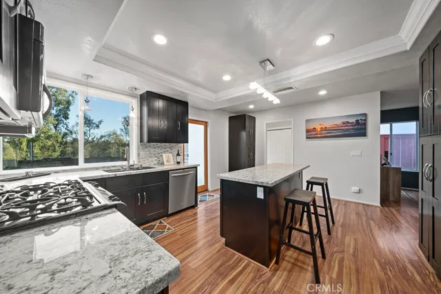 a kitchen with stainless steel appliances granite countertop a stove top oven a sink dishwasher a dining table and chairs with wooden floor