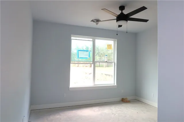 an empty room with a window and a fan