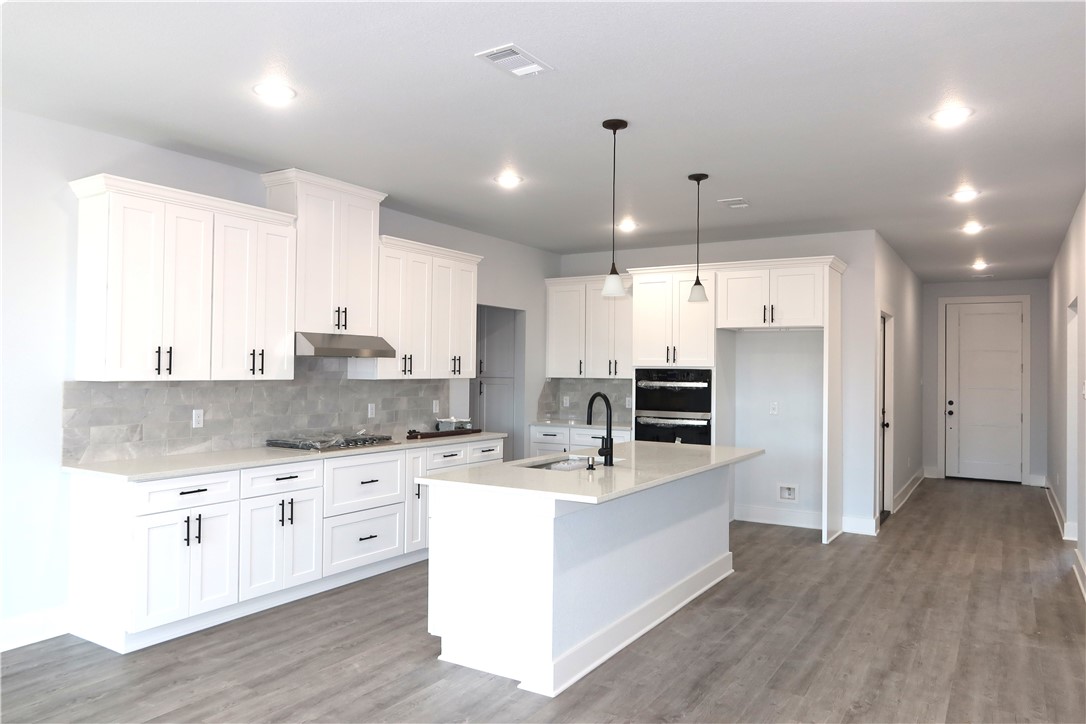 2014 Reagan Court Bryan, TX 77802 - Photo 8 of 22 a large kitchen with stainless steel appliances kitchen island granite countertop a stove a sink a refrigerator and white cabinets with wooden floor