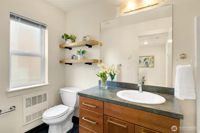 a bathroom with a granite countertop sink a toilet and a mirror