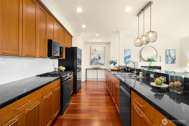 a large kitchen with stainless steel appliances granite countertop a stove a sink dishwasher and a microwave with wooden floor