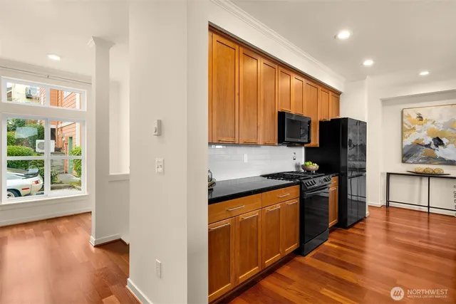 a kitchen with stainless steel appliances granite countertop wooden cabinets a stove top oven a sink and dishwasher with wooden floor