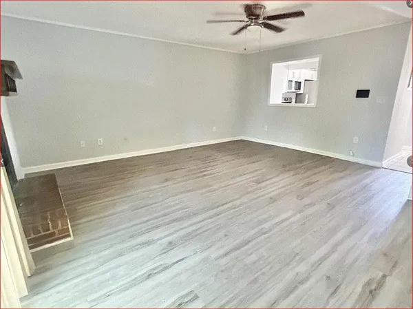 a view of an empty room with a window and wooden floor