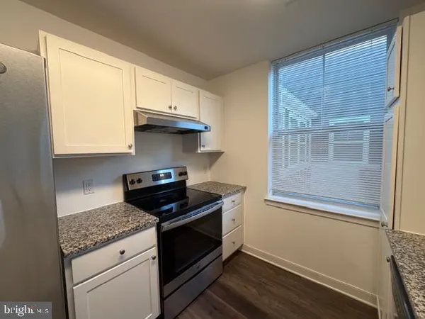 a kitchen with granite countertop wooden cabinets and a stove top oven