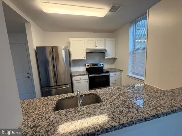 a kitchen with granite countertop a refrigerator and a sink