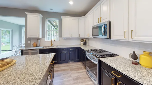 a kitchen with granite countertop a sink a stove and cabinets