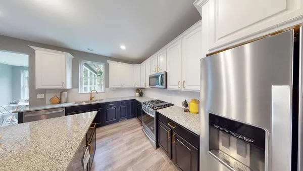 a large kitchen with stainless steel appliances granite countertop a refrigerator a sink dishwasher a stove with wooden cabinets