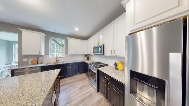 a large kitchen with stainless steel appliances granite countertop a refrigerator a sink dishwasher a stove with wooden cabinets