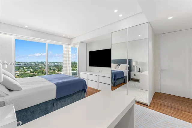 a bedroom with two beds a flat screen tv and a large window