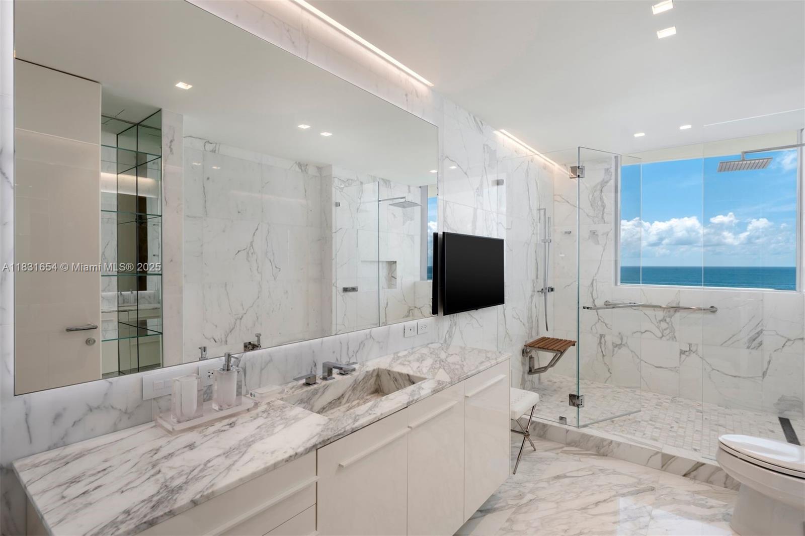 9349 Collins Avenue, Unit 1101 Surfside, FL 33154 - Photo 19 of 37 a bathroom with a granite countertop sink a toilet a mirror and shower