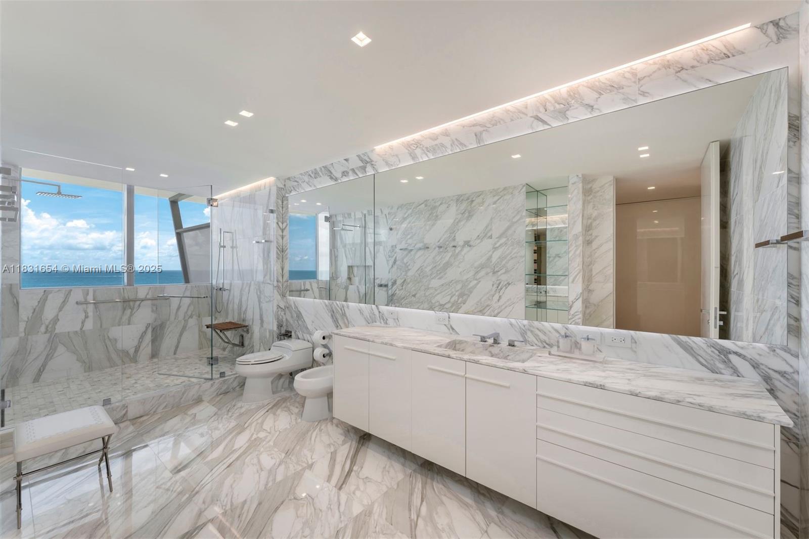 9349 Collins Avenue, Unit 1101 Surfside, FL 33154 - Photo 20 of 37 a bathroom with a double vanity sink a mirror and a bathtub