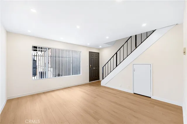 a view of an empty room with wooden floor and stairs