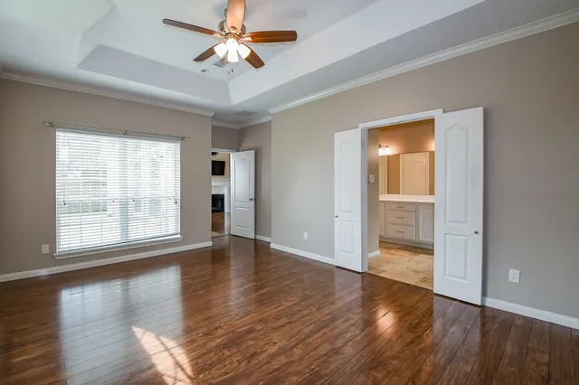 an empty room with wooden floor chandelier fan and windows