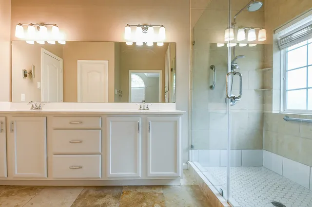 a bathroom with a double vanity sink mirror and shower