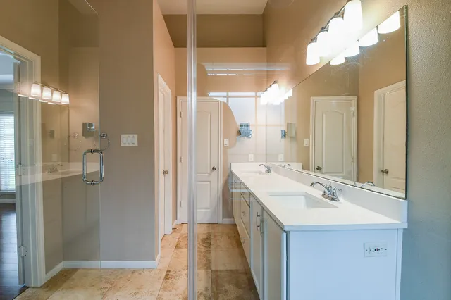 a bathroom with a double vanity sink mirror and shower
