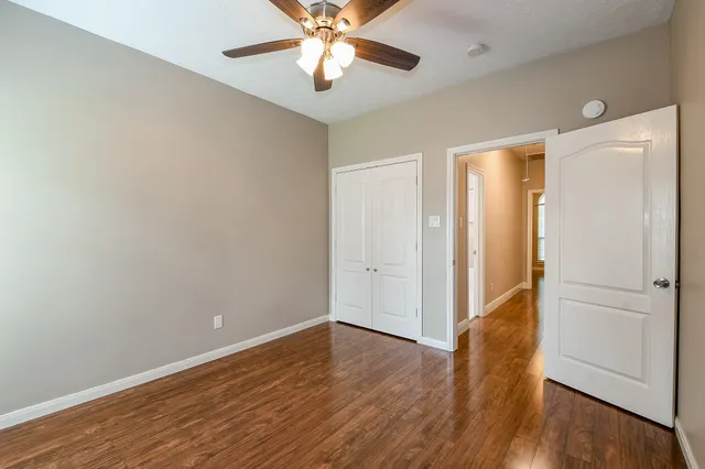an empty room with wooden floor and a ceiling fan