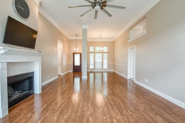 a view of an empty room with wooden floor fireplace and a window