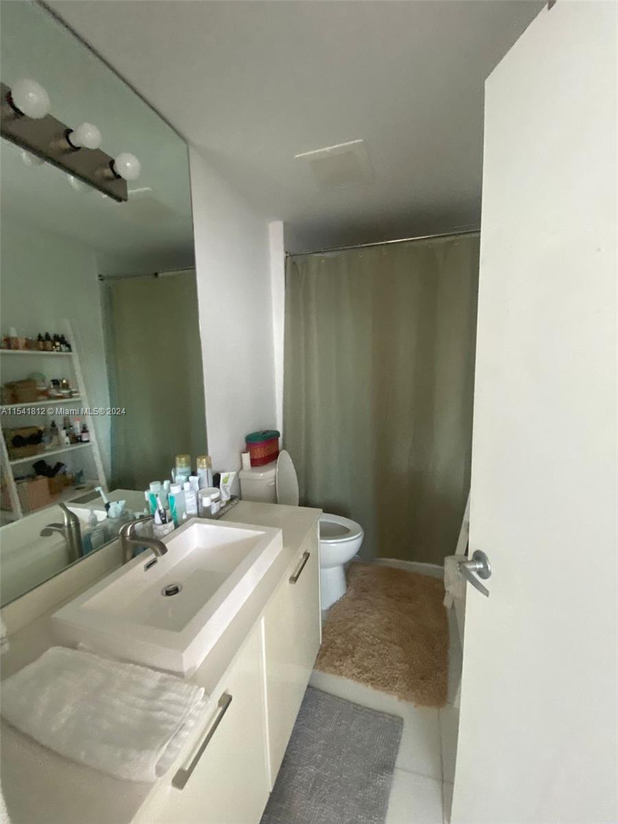 151 Southeast 1st Street, Unit 2707 Miami, FL 33131 - Photo 9 of 12 a bathroom with a sink and a mirror