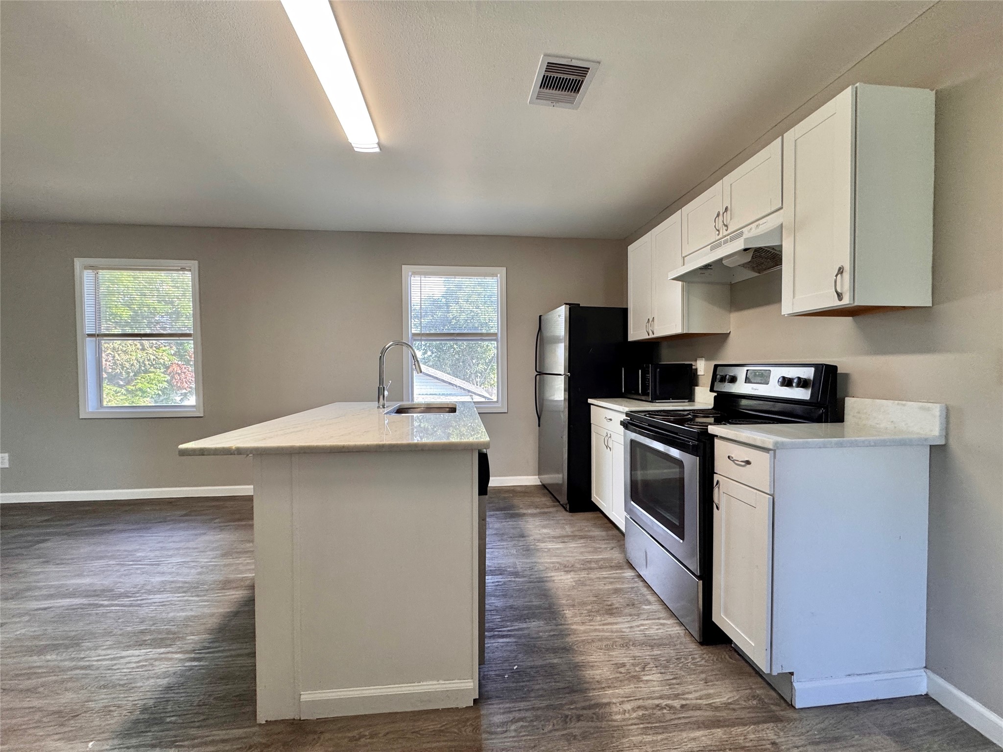 Kitchen is complete with electric stove, countertop microwave, refrigerator, and dishwasher.