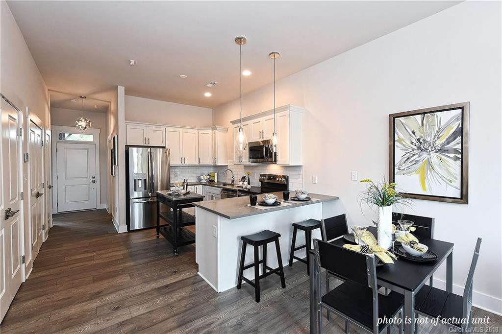 935 McAlway Road, Unit 201 Charlotte, NC 28211 - Photo 6 of 21 a kitchen with stainless steel appliances kitchen island granite countertop a stove a refrigerator a sink a dining table and chairs with wooden floor
