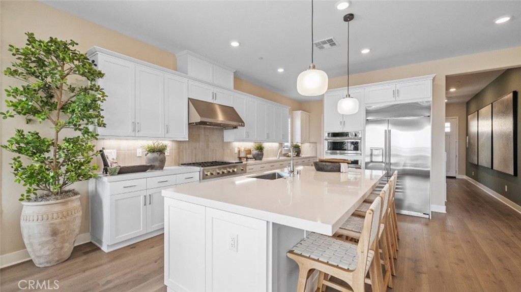 29503 Corte Azulejo Valencia, CA 91354 - Photo 2 of 34 a kitchen with a white center island a stove a dining table and chairs