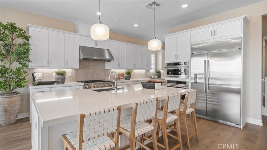 29503 Corte Azulejo Valencia, CA 91354 - Photo 5 of 34 a kitchen with stainless steel appliances a dining table chairs stove and refrigerator