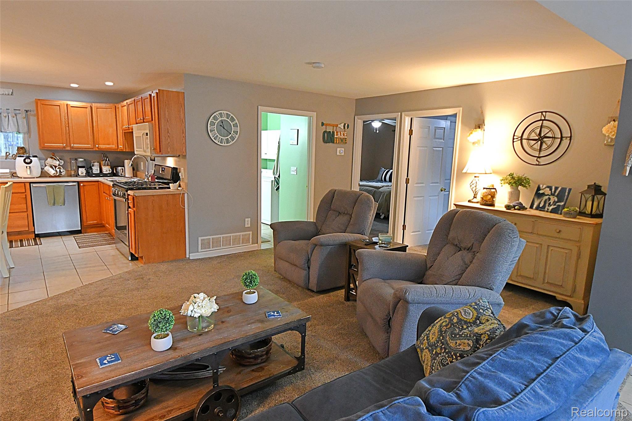 9611 Monroe Road St. Helen, MI 48656 - Photo 10 of 24 Open-concept living area featuring carpet flooring, a kitchen with wood-finish cabinetry, tile flooring, and stainless steel appliances