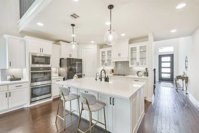 a large kitchen with kitchen island a refrigerator a stove a sink a dining table and chairs