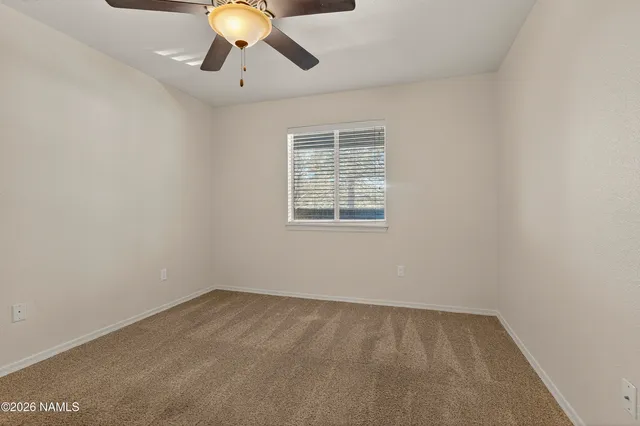 a view of an empty room with window and chandelier fan