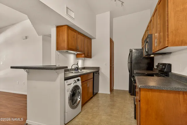 a kitchen with stainless steel appliances granite countertop a refrigerator a stove and a sink