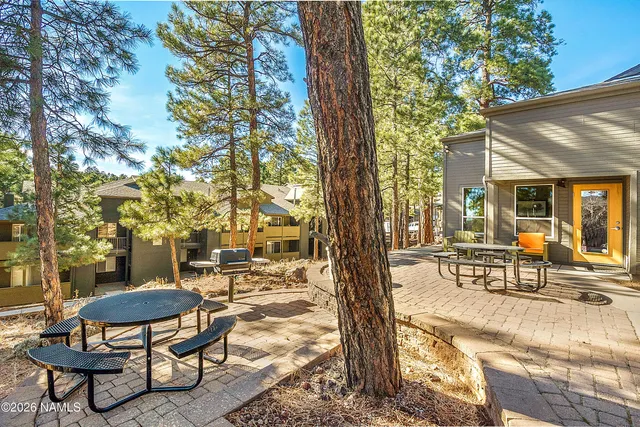 a patio with table and chairs and potted plants