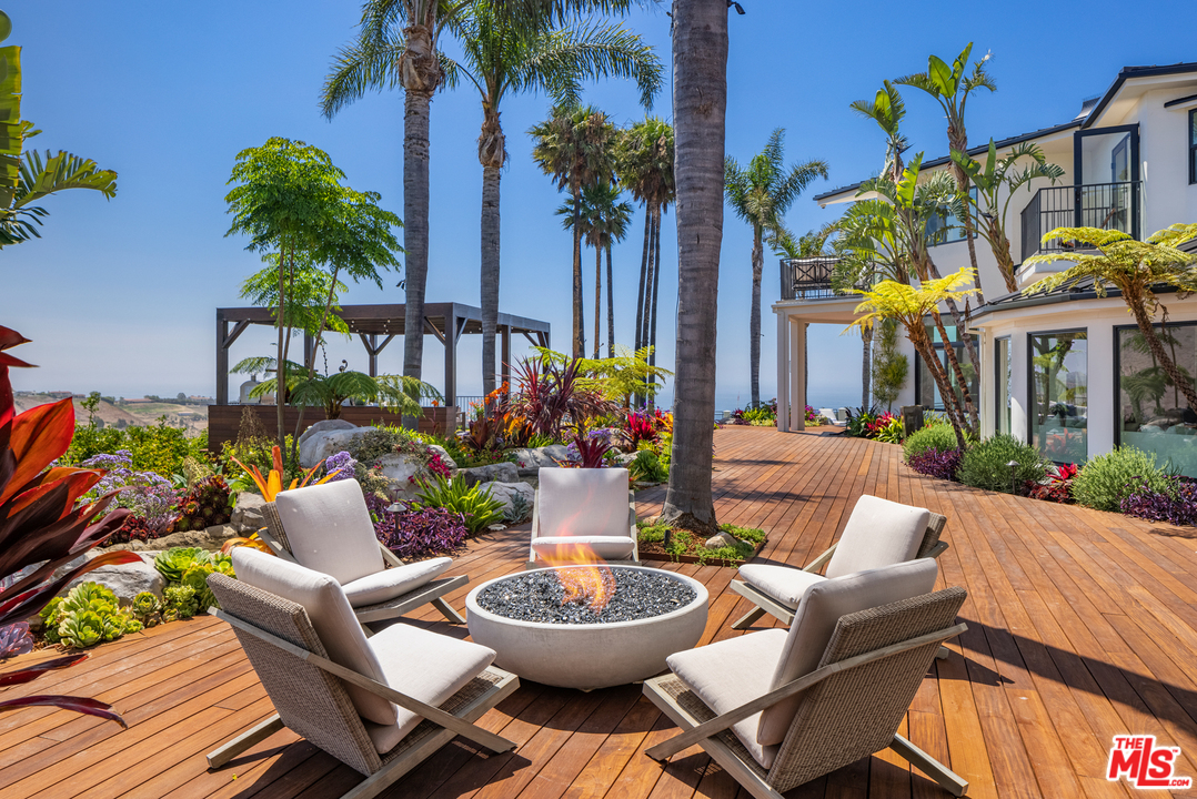 5868 Zumirez Drive Malibu, CA 90265 - Photo 25 of 54 a view of a patio with couches table and chairs potted plants and palm tree