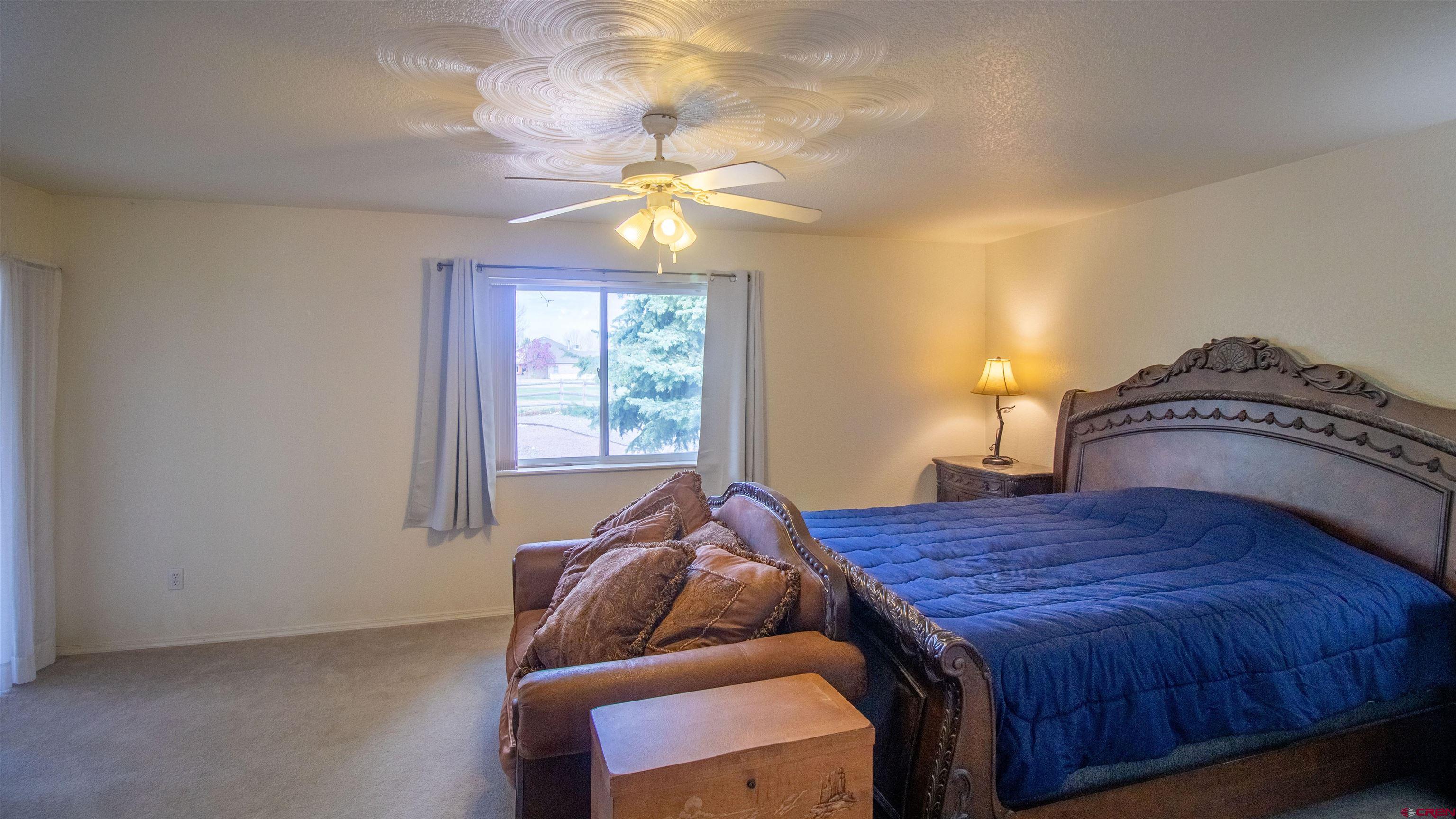 609 Heather Lane Montrose, CO 81401 - Photo 11 of 34 a bedroom with a bed and a chandelier