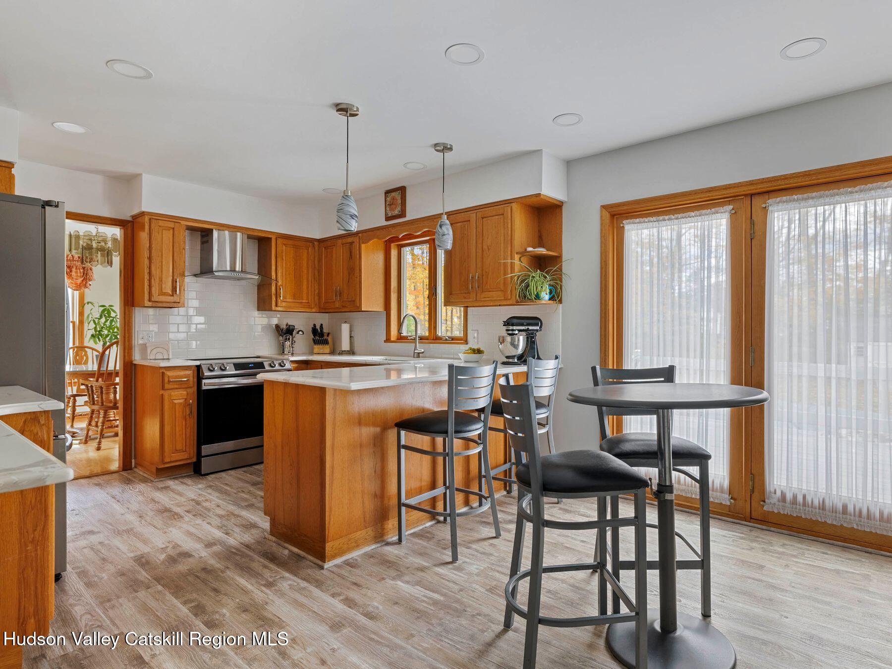 15 Ruby Meadows Road Lake Katrine, NY 12449 - Photo 19 of 53 a kitchen with stainless steel appliances granite countertop a stove top oven a sink dishwasher a dining table and chairs with wooden floor