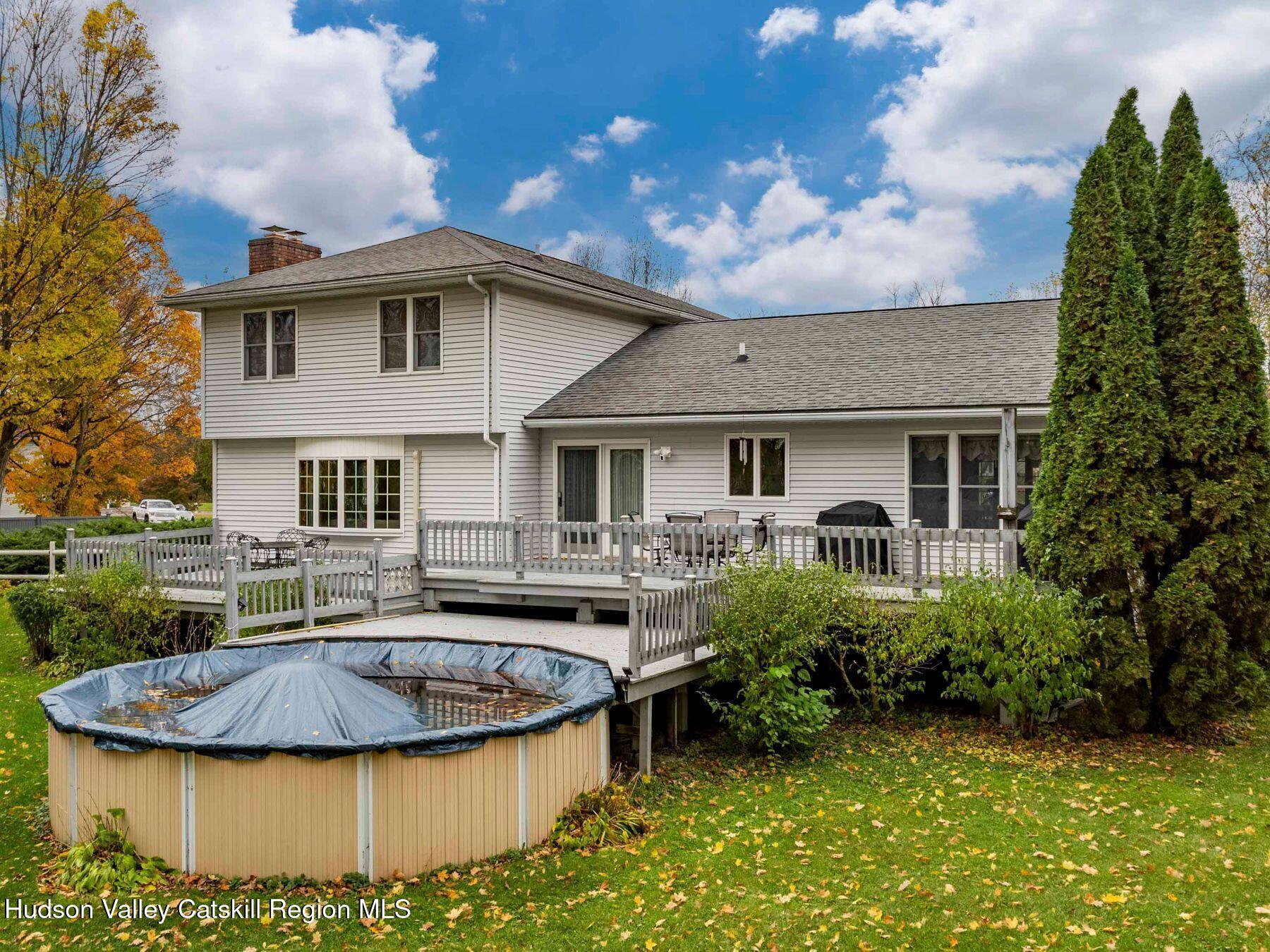 15 Ruby Meadows Road Lake Katrine, NY 12449 - Photo 42 of 53 a view of a white house with a swimming pool and a yard table and chairs