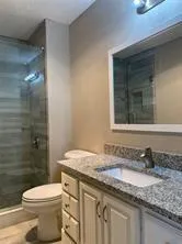 a bathroom with a granite countertop sink toilet and shower