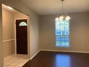 a view of a room with wooden floor chandelier and windows