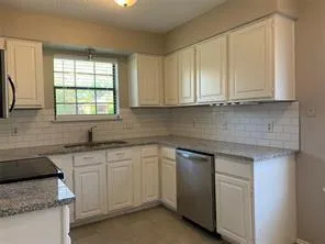 a kitchen with granite countertop white cabinets and a sink